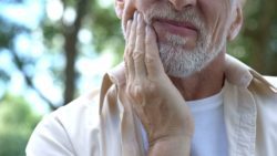 Older man holding his hand to his cheek in pain tooth extraction general dentistry dentist in Jacksonville Florida