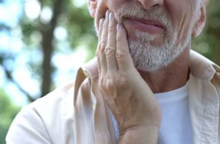 Older man holding his hand to his cheek in pain tooth extraction general dentistry dentist in Jacksonville Florida