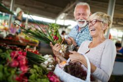 Smiling senior couple holding basket with vegetables at the grocery shop tooth extraction root canal general dentistry dentist in Jacksonville Florida