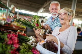 Smiling senior couple holding basket with vegetables at the grocery shop tooth extraction root canal general dentistry dentist in Jacksonville Florida